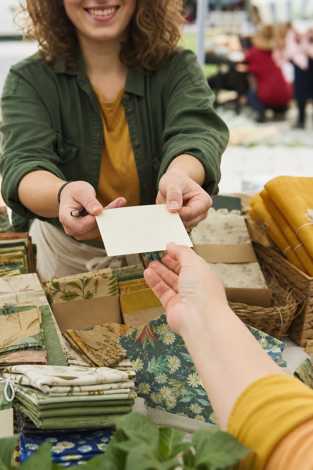 AI-generated illustrative concept art showing a maker offering a blank signup card to a visitor at a craft-fair stall.