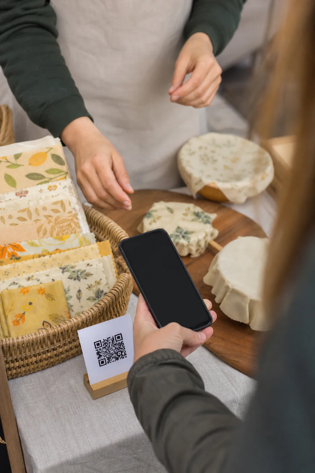 AI-generated illustrative concept art of a visitor using a phone beside a QR-style card at a craft fair; the code is decorative and nonfunctional.