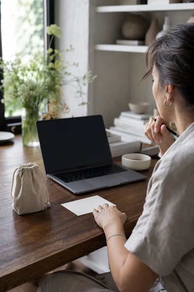Maker editing at a desk beside a plain product and turned-away laptop.